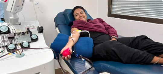 Mujer donando sangre recostada en un sillón del banco de sangre