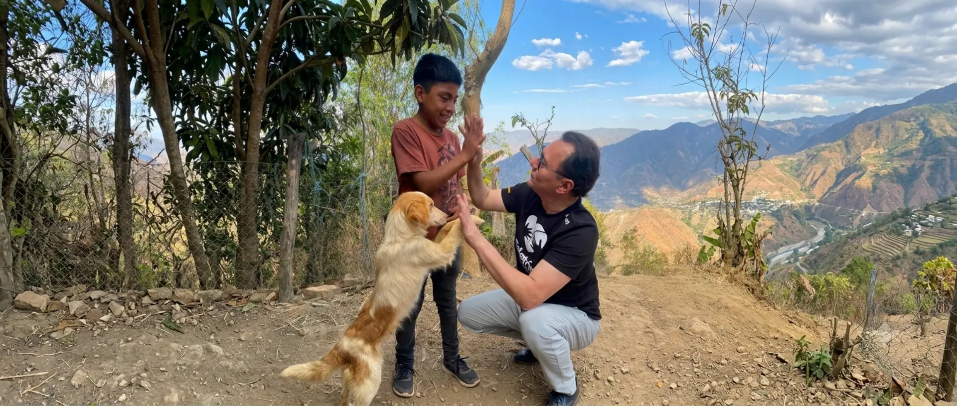 Niño chocando la mano con un donante de Teletón junto a su perro, en un paisaje de montaña