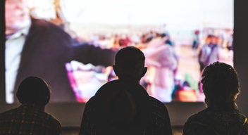 Tres personas en la oscuridad miran a una pantalla iluminada. Foto por Aneta Pawlik para Unsplash.