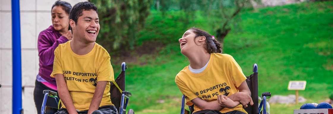 Dos usuarios de silla de ruedas platican y ríen en una cancha de baloncesto