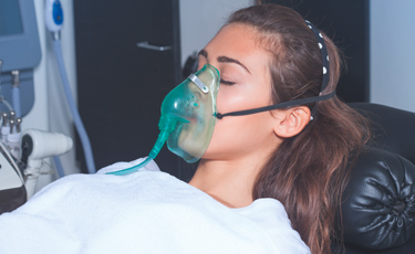Fotografía de mujer con respirador y los ojos cerrados durante terapia respiratoria.