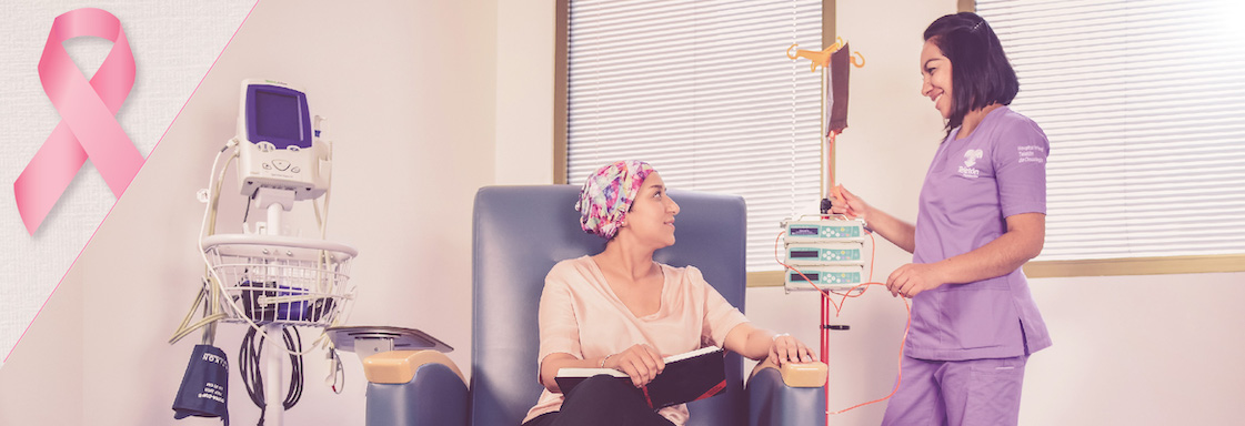 Fotografía de una mujer recibiendo quimioterapia en el HITO. Junto a ella está una enfermera con bata morada.