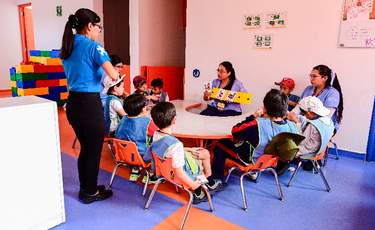 Terapeutas y niños sentados en mesa de trabajo en aula del Centro Autismo Teletón